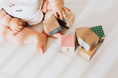 kaboompics_Detail of a newborn baby feet - wooden blocks - toys